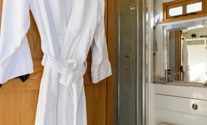 The bathroom itself is compact but it boasts a full-size shower, luxurious bathrobes, and handmade bathroom products.